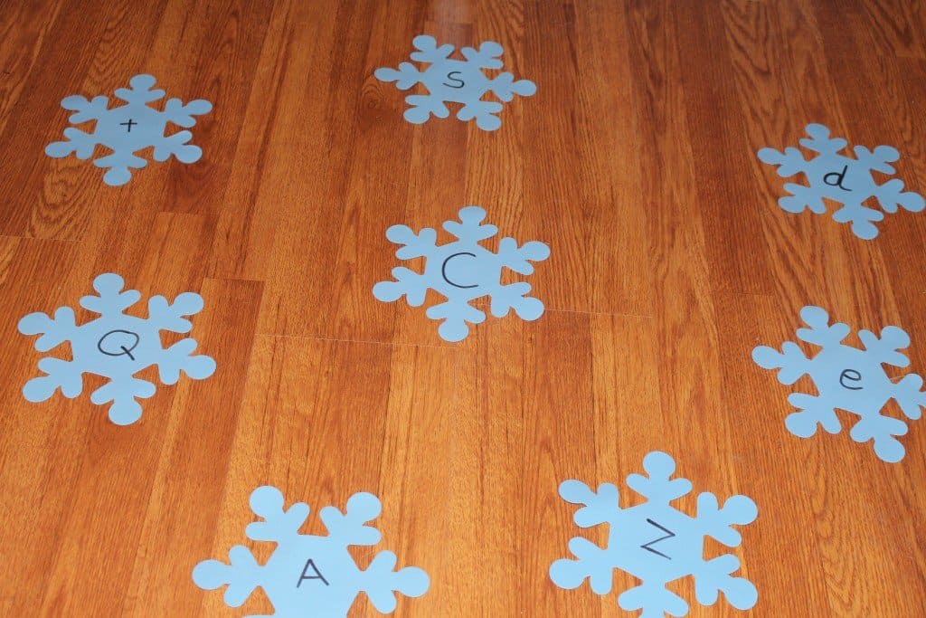 a variety of lettered foam snowflakes spread out on a wodden floor