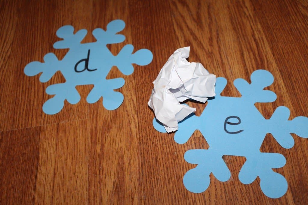 a crumpled paper ball laying on top of a foam snowflake with the letter e on it