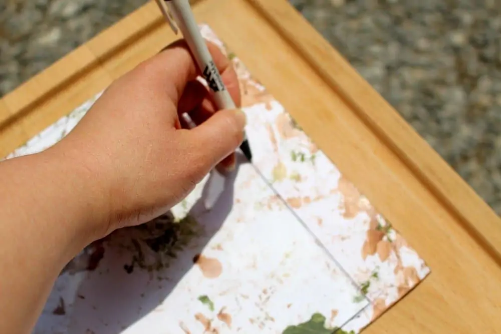 adult trimming the paper to fit a square frame