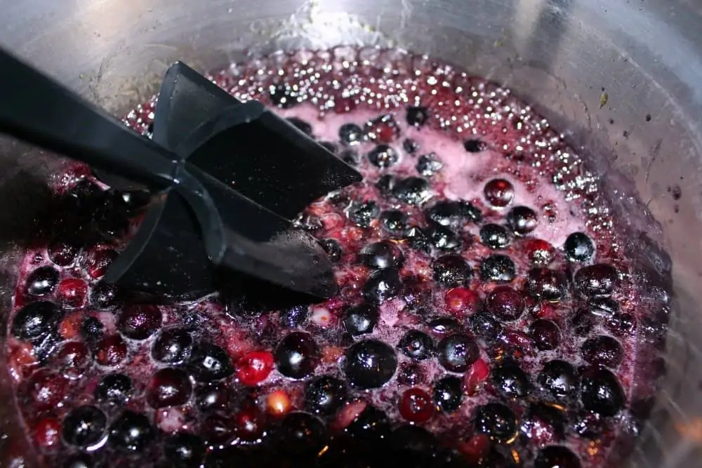 blueberries being cooked down in a hot pot to make Blueberry Syrup