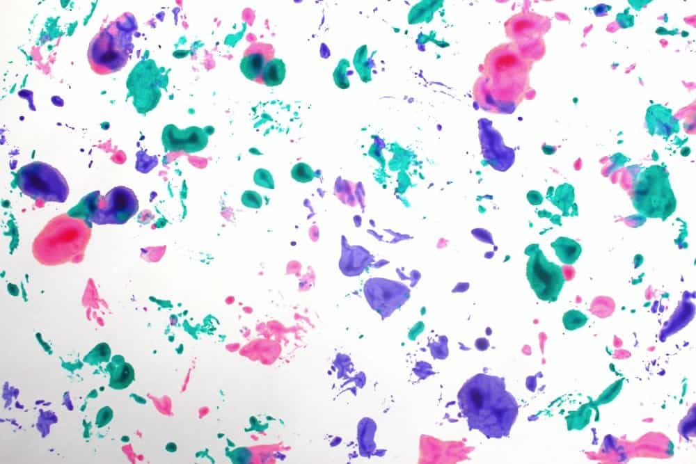 Finished paint tranfer process art with splotches of paint in teal, purple, and pink