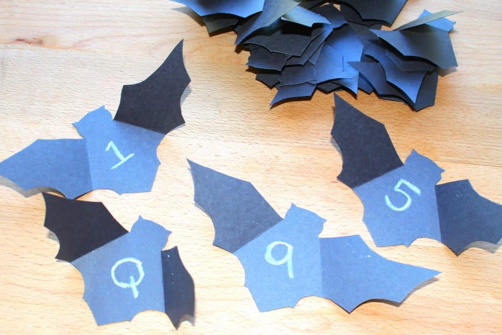 black construction paper bats with letters and numbers written on them in white