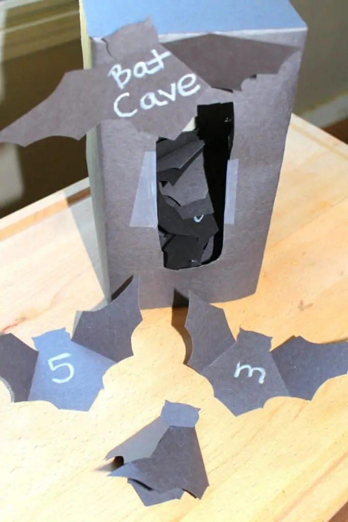 tissue box covered in black contruction paper with the whole cute out labeled "bat cave"