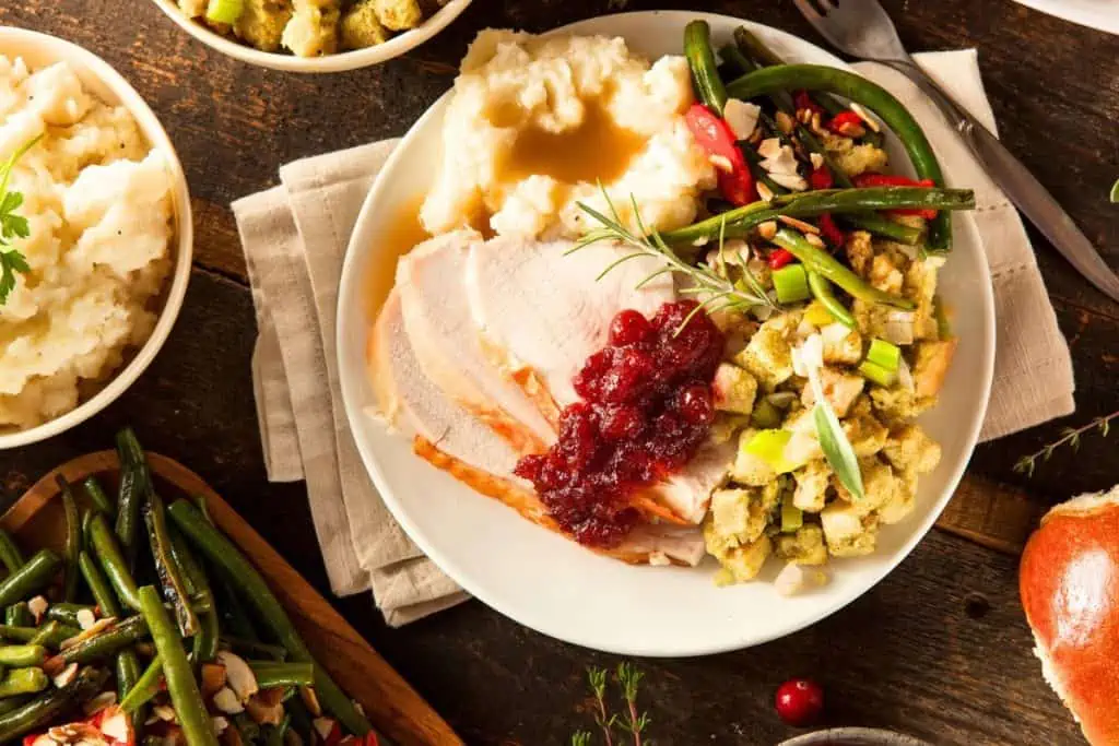 Thanksgiving dinner on the table with turkey, cranberry sauce, stuffing, an d potatoes. 