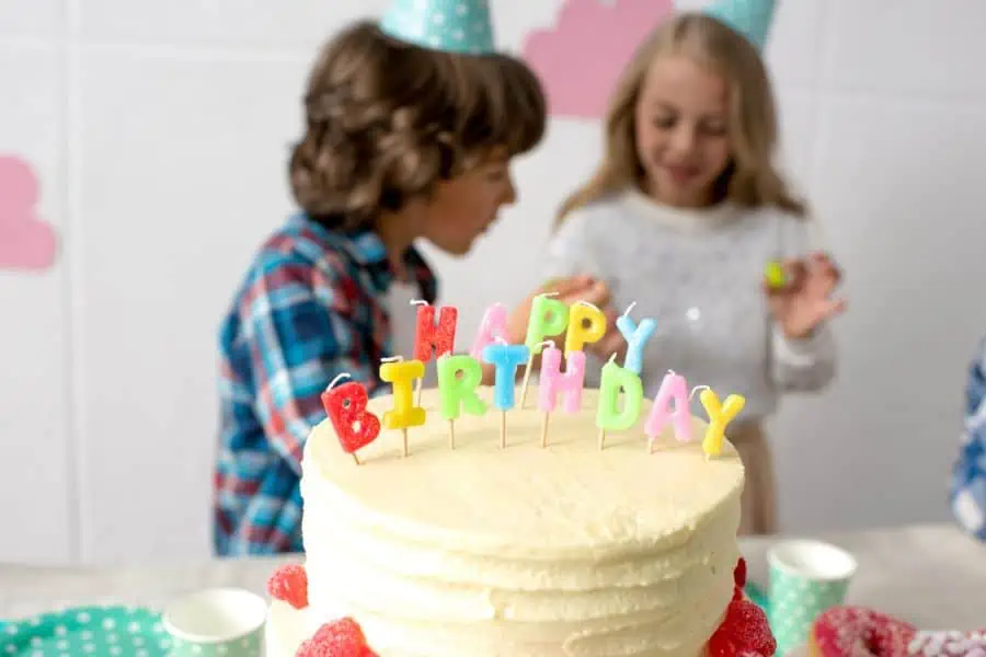Happy kids behind birthday cake with candle