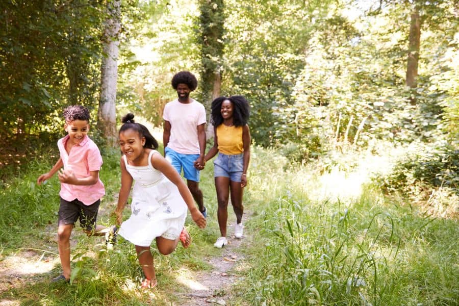 Happy black family walking in woods representing summer fun in Knoxville