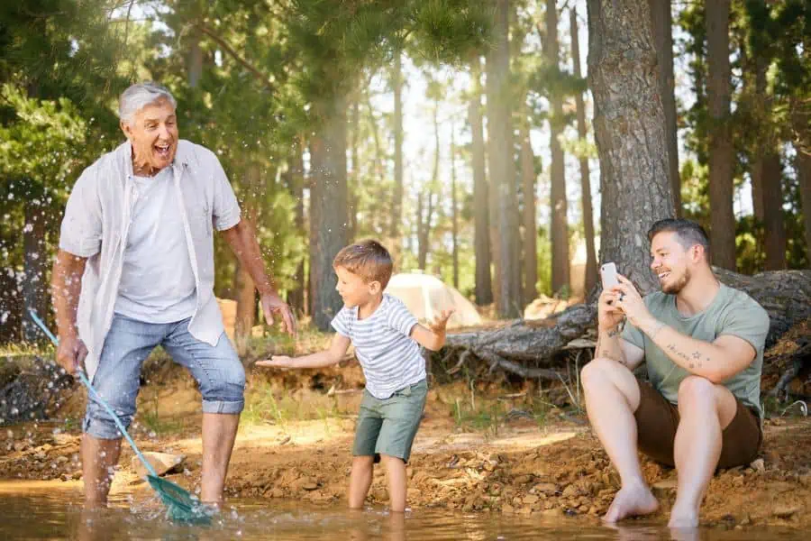 grandfather, father and son playing and fishing in a creek.
