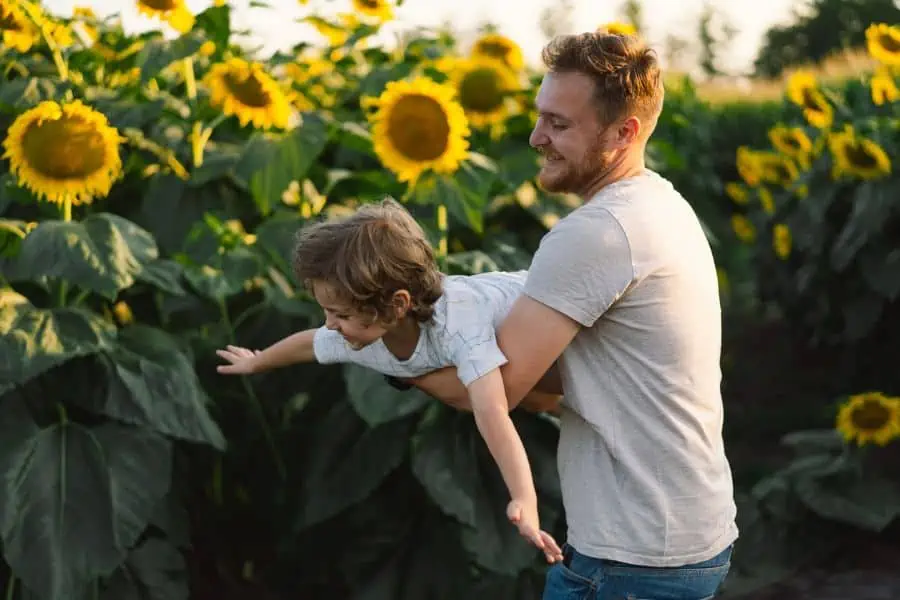 happy father and son playing a sunflower field.