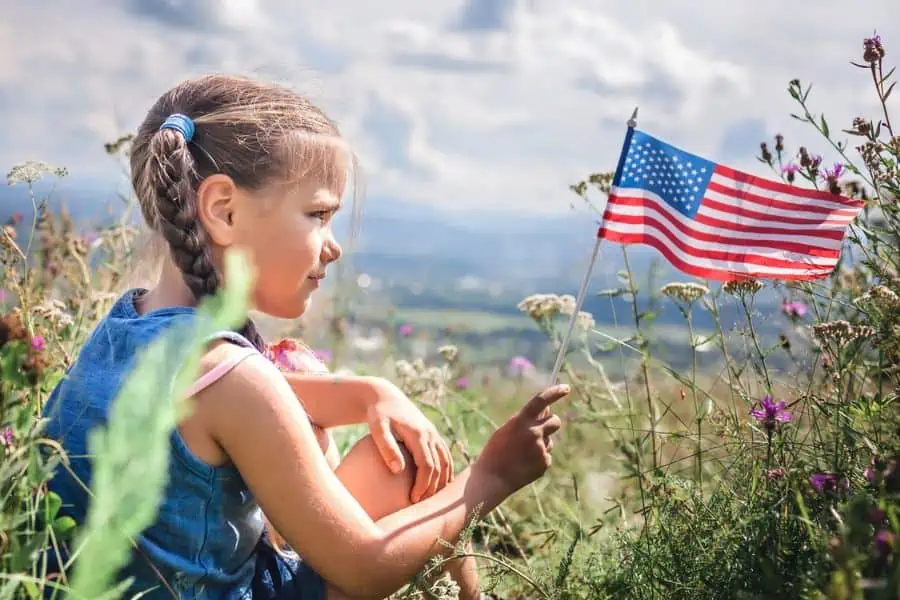 Girl in front of mountain scenery waving an American flag