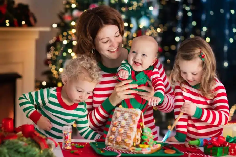 Happy family in Christm as pajamas making a gingerbread house