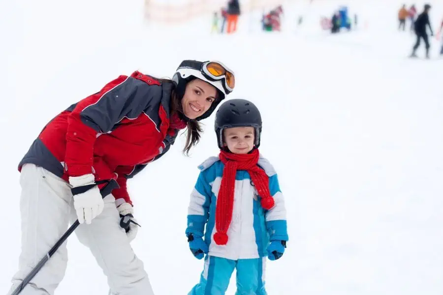 happy mother and son smiling at the bottom of a ski slope
