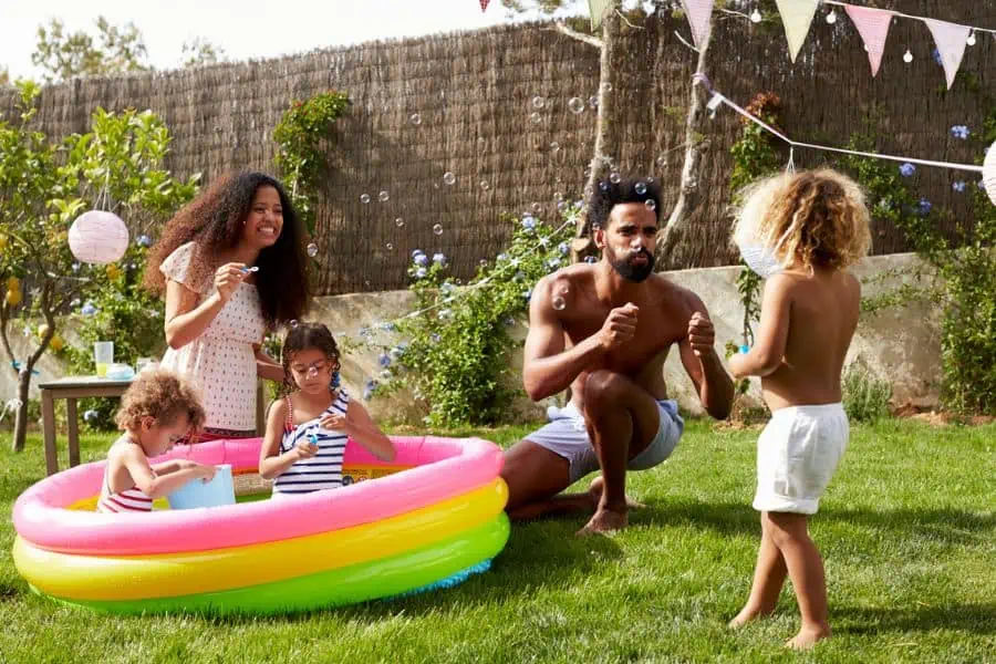 Happy family swimming in a rainbow kiddie pool in backyard reepresenting things to do in Knoxville in August