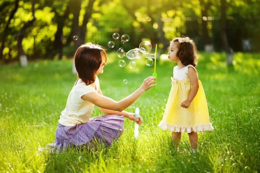 Mother and daughter blowing bubbles in a grassy field representing things to do in Knoxville in September