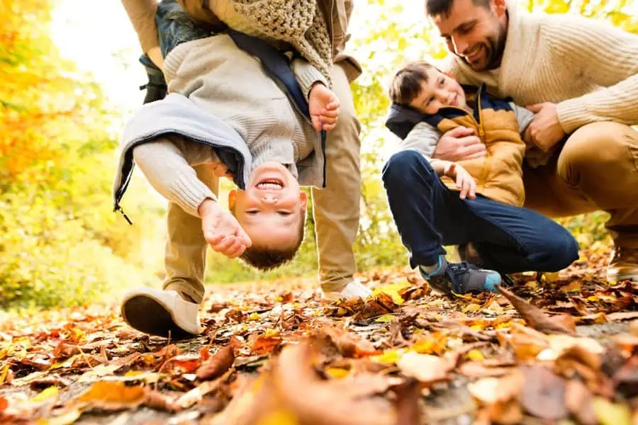 Happy family playing in a pile of colorful fall leaves representing fall activities in Knoxville TN