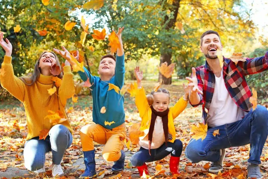 happy family playing in fall leaves representing things to do in Knoxville in October