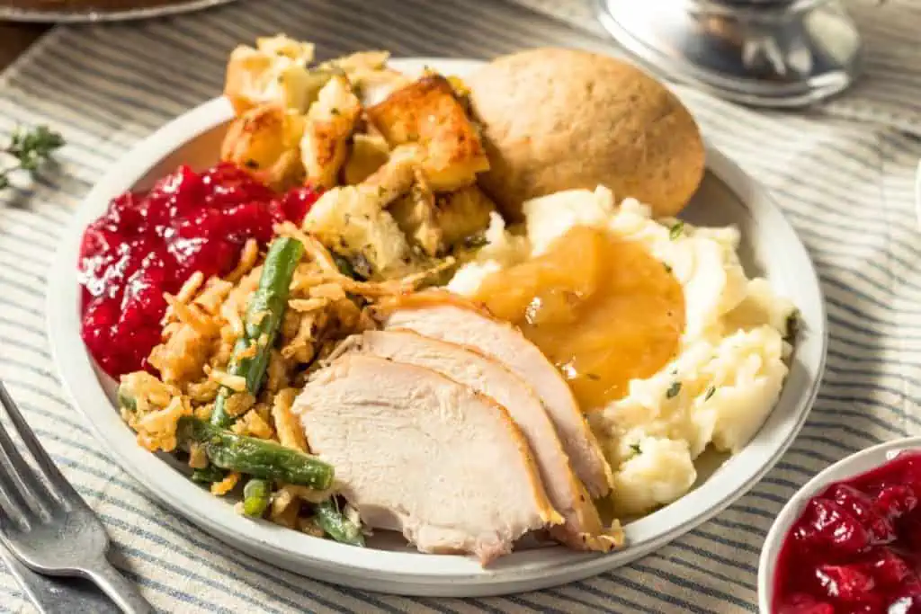 yummy looking turkey dinner on a plate with mashed potatoes, gravy, green beans, and a dinner roll. 