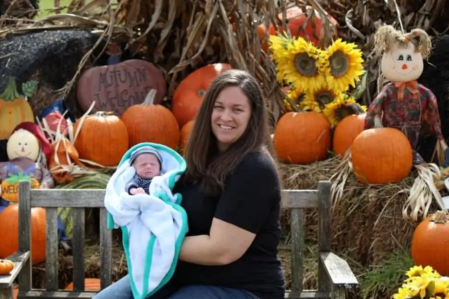 mother and son posing in front of a fall display of pumpkins and scarecrows