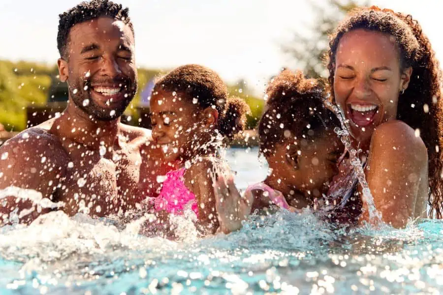 Happy mother, father, and daughters swimming in pool representing indoor pools in Johnson City TN.