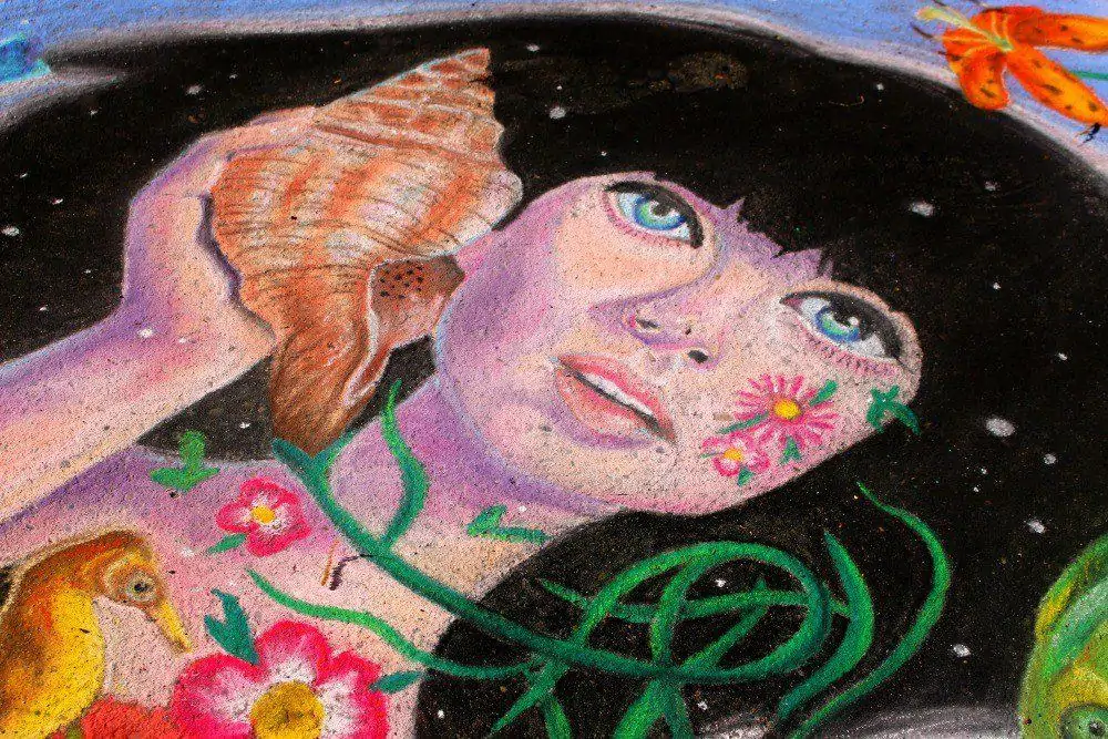 a colorful chalk drawing of a black-haired mermaid holding a shell. 