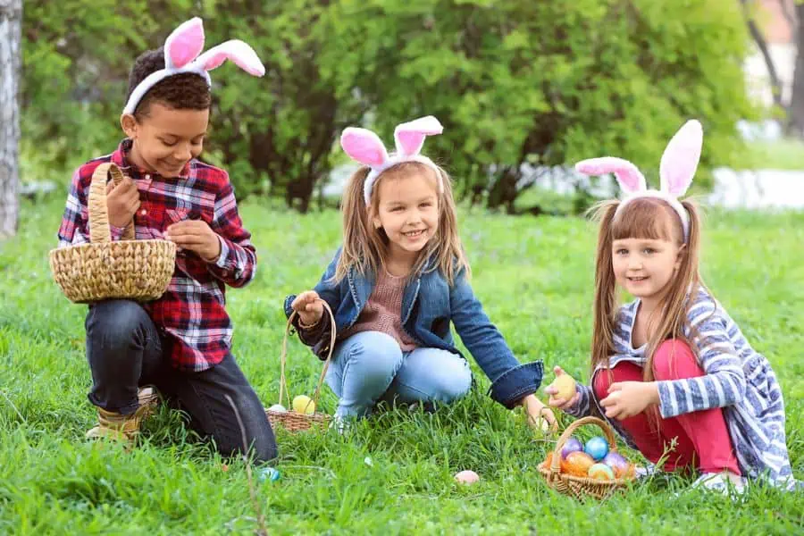 3 young children collects Easter eggs in a field representing Chattanooga easter Egg hunts