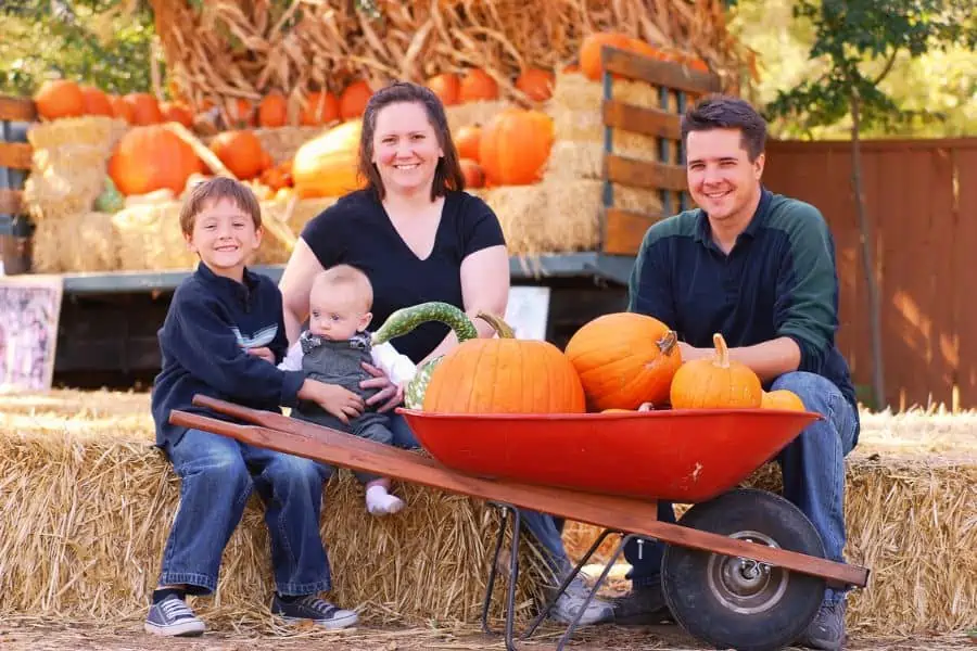 Happy family posing for a picture at a pumpkin farm.