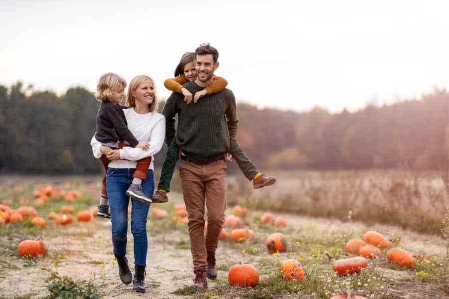 Happy Family walking through pumpkins representing pumpkin farms near Chattanooga