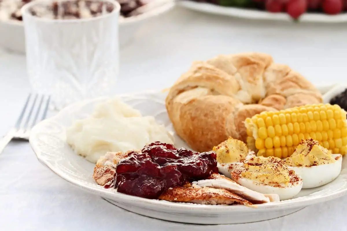 white plate turkey and cranberry sauce, corn, and a roll, representing Johnson City TN restaurants open Thanksgiving
