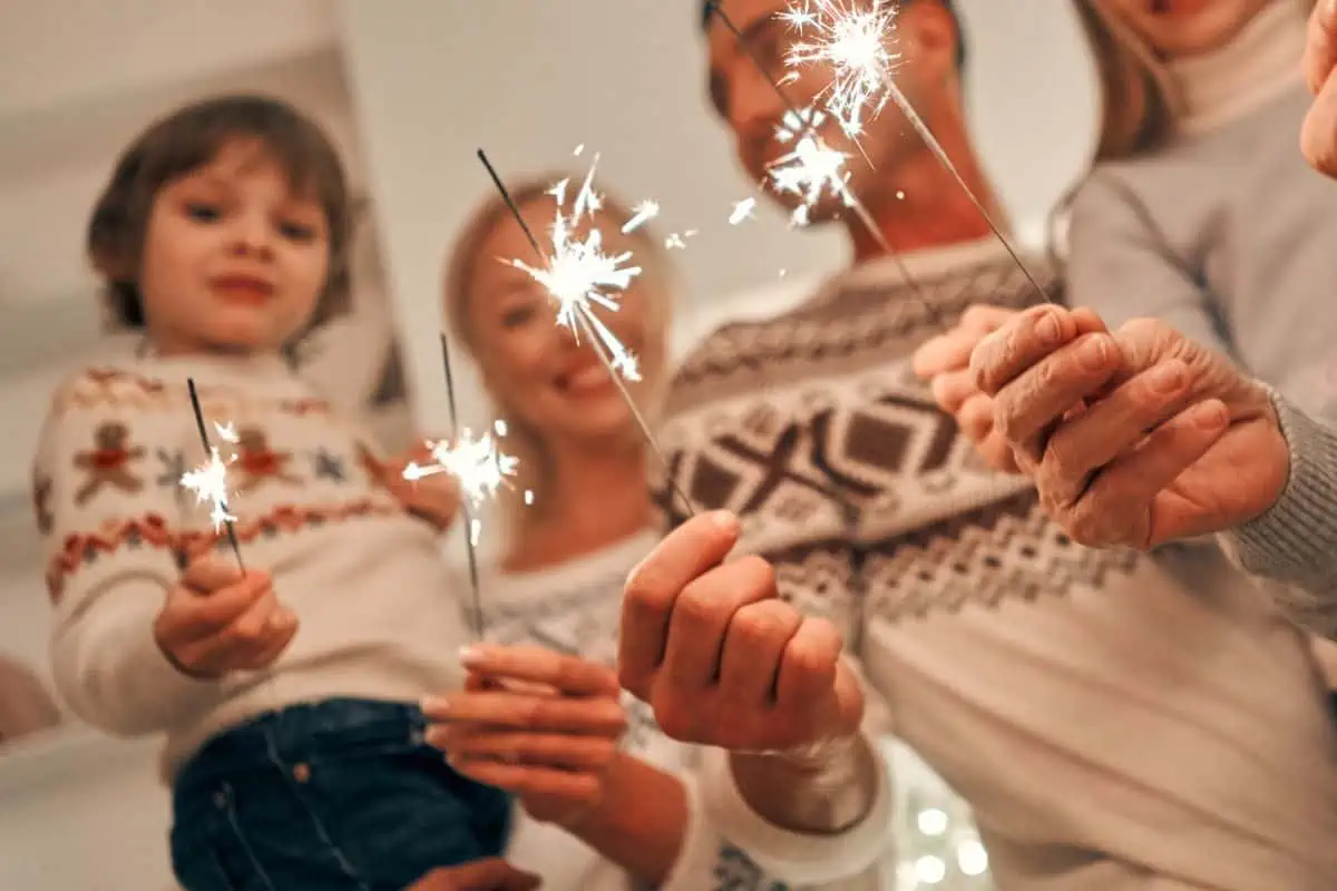 Happy family in warm sweaters holding lit sparklers representing New Year's Events in Chattanooga TN