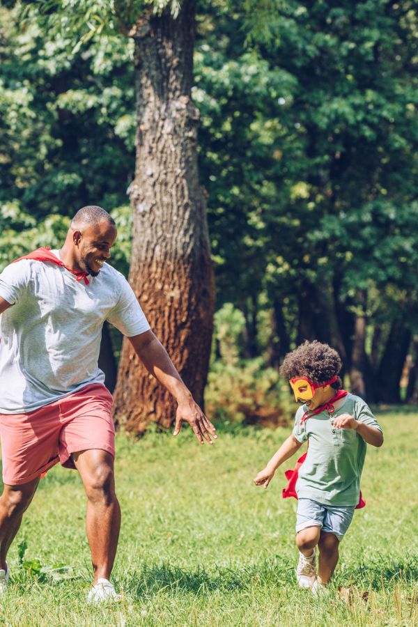 father and son playing in sunny yard with capes and masks representing summer activities in Tri-Cities TN