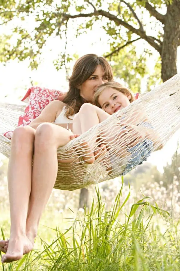 Mother and daughter snuggling on hammock in the sun, representing things to do in Chattanooga in July.