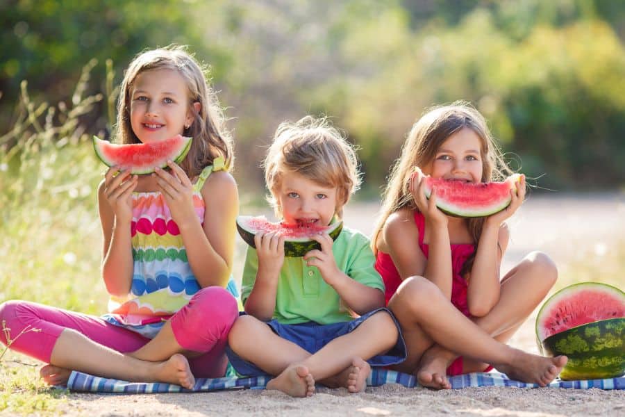 Happy kids eating watermelon representing July events in Tri-Cities TN