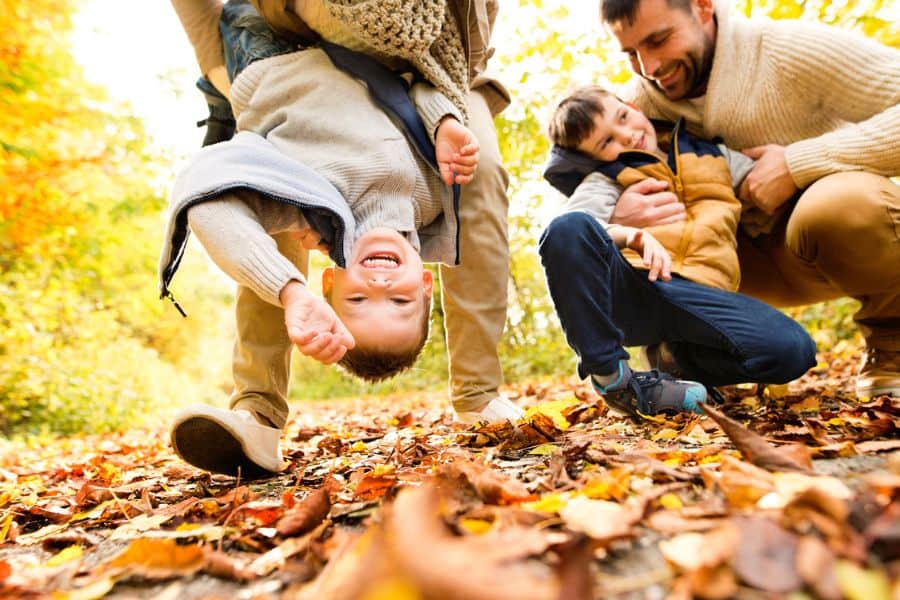 Happy family plaing in a pile of colorful fall leaves representing fall activities in Knoxville TN