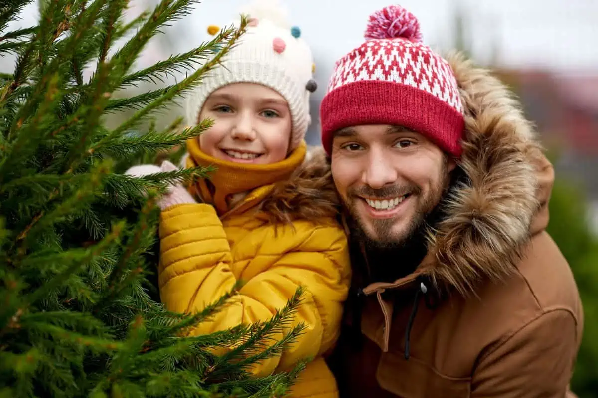 happy father and daughter with Christmas tree at farm representing Christmas tree farms near Knoxville TN.